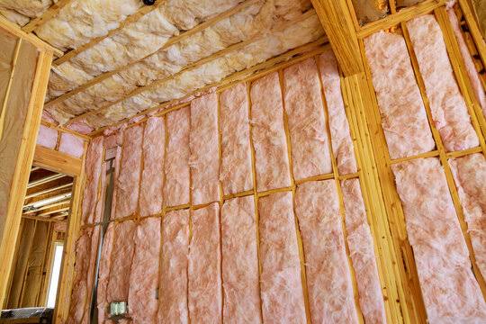 Fiberglass batt insulation installed between wall studs and ceiling joists in a framed home